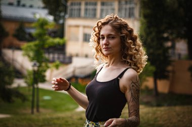 Sokakta dövmeleri olan kıvırcık saçlı, tatlı bir kadın.