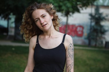 Sokakta dövmeleri olan kıvırcık saçlı, tatlı bir kadın.