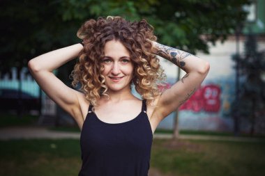 Sokakta dövmeleri olan kıvırcık saçlı, tatlı bir kadın.