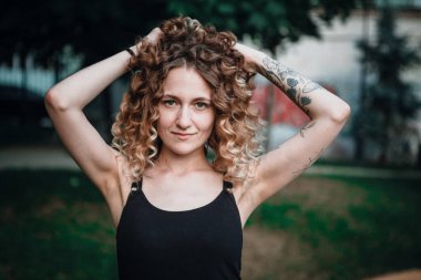 Sokakta dövmeleri olan kıvırcık saçlı, tatlı bir kadın.