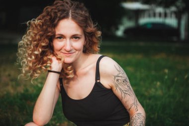 Sokakta dövmeleri olan kıvırcık saçlı, tatlı bir kadın.