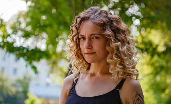 Sokakta dövmeleri olan kıvırcık saçlı, tatlı bir kadın.