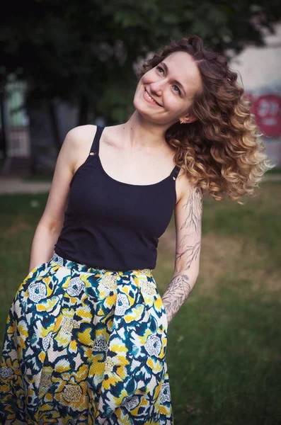 Sokakta dövmeleri olan kıvırcık saçlı, tatlı bir kadın.