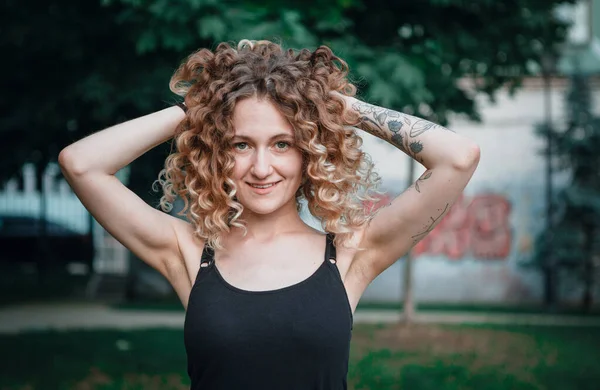 Sokakta dövmeleri olan kıvırcık saçlı, tatlı bir kadın.