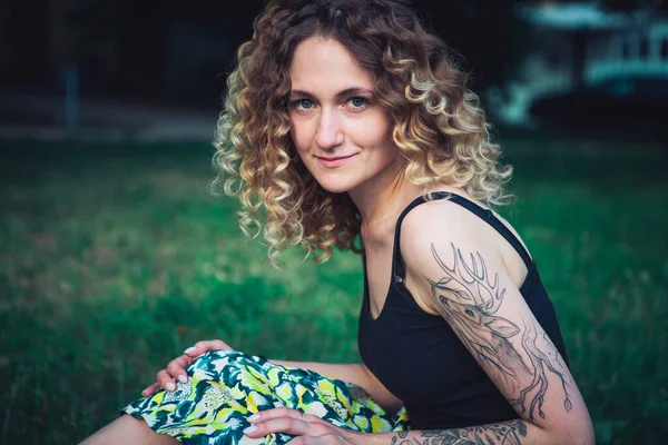 Sokakta dövmeleri olan kıvırcık saçlı, tatlı bir kadın.