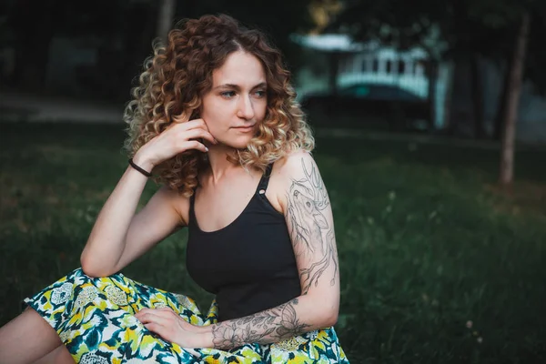 Sokakta dövmeleri olan kıvırcık saçlı, tatlı bir kadın.