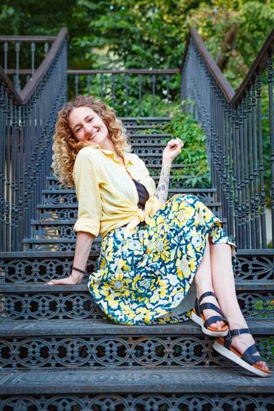 Merdivenlerde sarı tişörtlü, dövmeli güzel genç bir kadın.