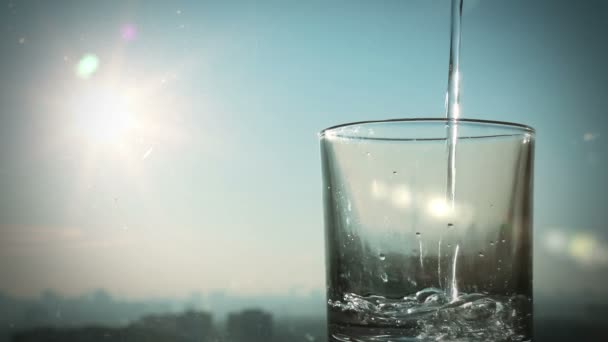 Konzeptionelle Aufnahmen von Wasser auf einem Hintergrund aus verschwommener Stadt und Sonne, voller — Stockvideo