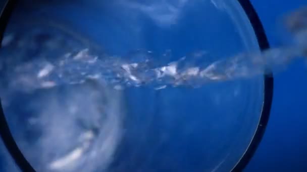 Vidro de água sobre um fundo azul — Vídeo de Stock