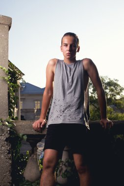 androgyne çocuk sokakta poz. Bak. gri gömlek, siyah şort. kuyruk saç modeli