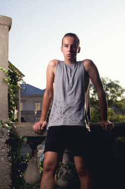 Androgyne boy posing on street. look. grey t-shirt, black shorts. tail hairstyle clipart