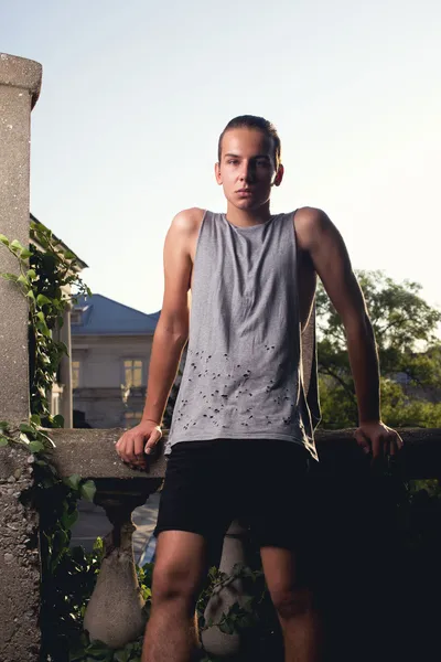 Androgyne boy posing on street. look. grey t-shirt, black shorts. tail hairstyle — Stock Photo, Image