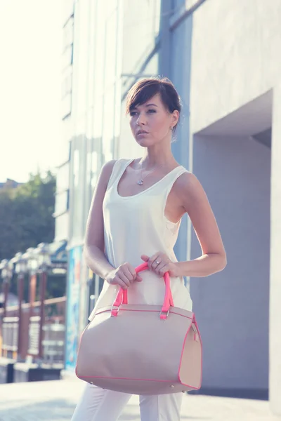 Model holding handbag outdoor.beige blouse. white shirt. beige leather bag. high heels — Stock Photo, Image