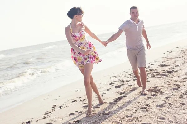 Imagen dinámica de una pareja corriendo en la playa. Tomados de la mano. Diversión veraniega — Foto de Stock