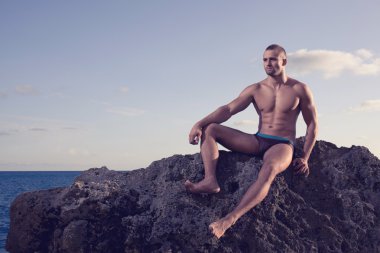 sahil üzerinde poz güzel bir adam. siyah şort, siyah mayo. kısa saçlı. ciddi bir görünüm