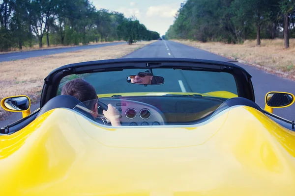 Male driver steering convertible car with open roof. Back view — Stock Photo, Image