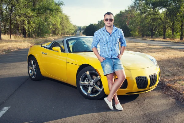 Joven conductor masculino de pie cerca de su coche deportivo —  Fotos de Stock