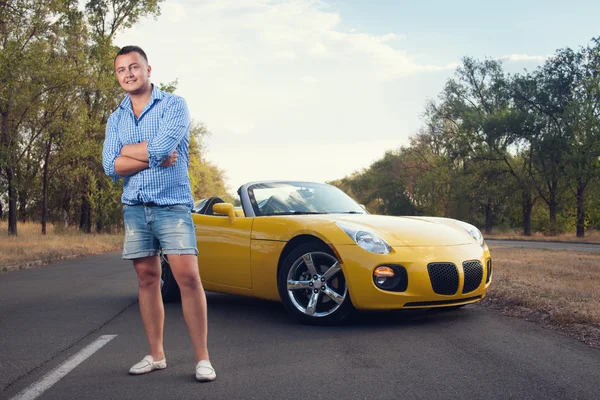 Unga trendiga manliga förare med sin Cabriolet gul bil — Stockfoto