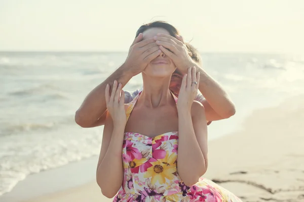 Hombre joven cubriendo los ojos de su novia en la playa durante el verano diversión al aire libre — Foto de Stock
