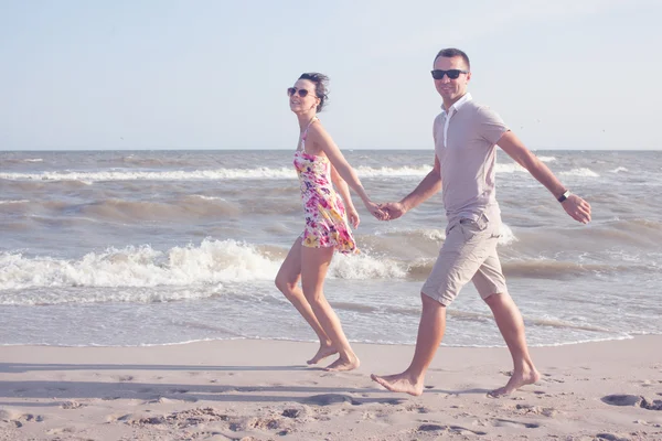 Un disparo de feliz pareja sonriente. Caminando por la playa. Sujetándose y sonriendo —  Fotos de Stock