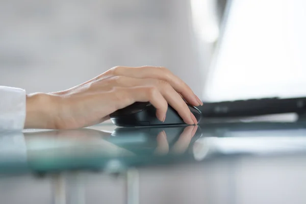 Mão das mulheres usando mouse sem fio na mesa de vidro — Fotografia de Stock