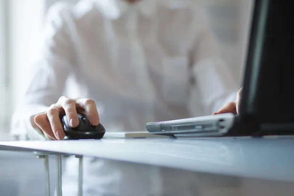 Mão das mulheres usando mouse sem fio na mesa de vidro — Fotografia de Stock