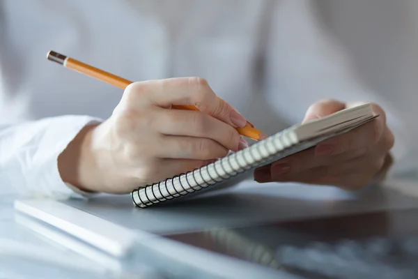 Frauen schreiben Zettel mit Bleistift auf Notizblock — Stockfoto