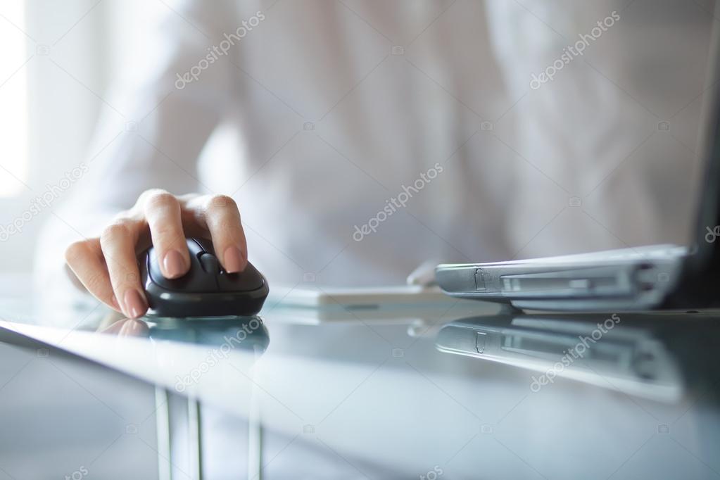 Womans hand using cordless mouse on glass table