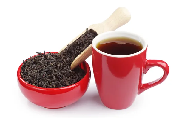 Cup of tea and dry black tea in a red bowl — Stock Photo, Image