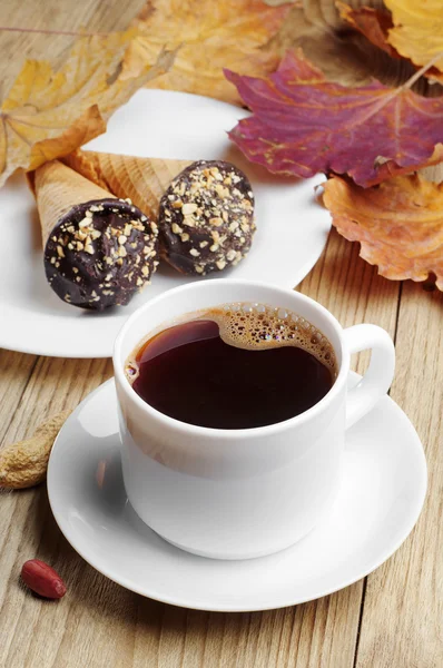 Cup of hot coffee with cakes in cream cone