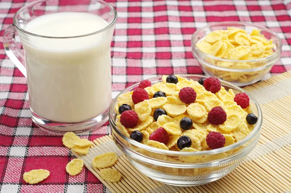 Чаша кукурузных хлопьев с ягодами и чашкой молока — стоковое фото