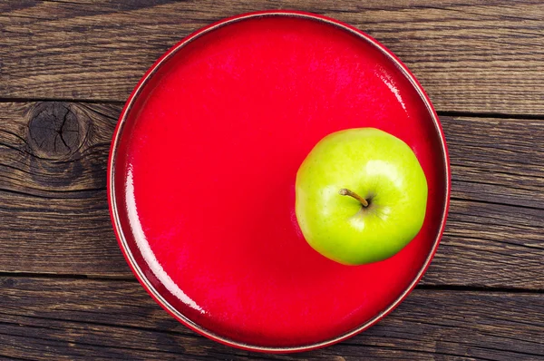 Pomme verte sur une assiette rouge — Photo