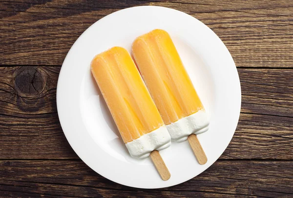 Två orange popsicle i en tallrik — Stockfoto