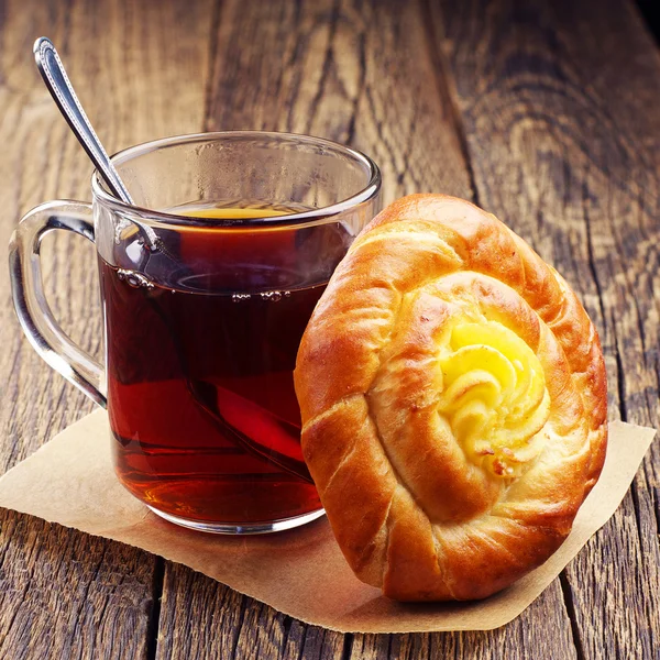 Bun with custard and tea — Stock Photo, Image