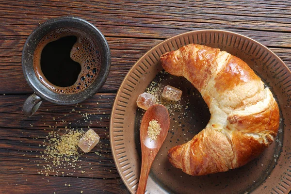 最新烘焙的羊角面包和一杯咖啡放在木制桌面上 — 图库照片