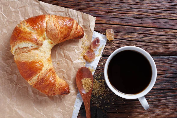 Frisch Gebackenes Croissant Und Eine Tasse Kaffee Auf Der Holztischplatte — Stockfoto