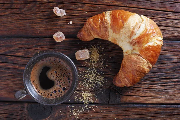 最新烘焙的羊角面包和一杯咖啡放在木制桌面上 — 图库照片