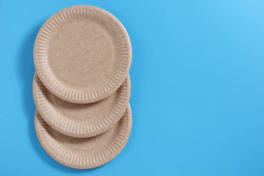 Mavi arkaplan üzerinde tek kullanımlık kahverengi kağıt plakalar, kopya alanı ile üst görünüm