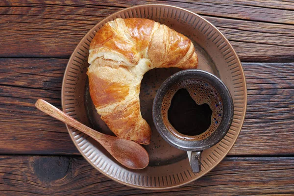 最新烤的羊角面包和一杯咖啡放在木制桌子上的盘子里 俯瞰全景 — 图库照片