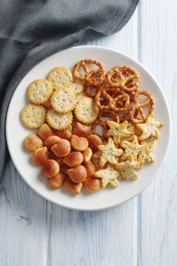 Küçük krakerler farklı şekilleri tabakta mavi ahşap masada karıştırıyor.