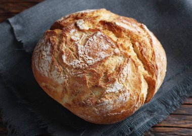 Küçük bir somun ekmek, ahşap masanın üzerinde. Yakın plan.