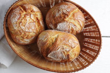 Hasır sepetin üzerindeki küçük ekmekten taze pişmiş beyaz masa, üst manzara. 