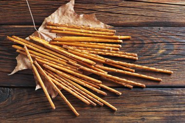 Sonbahar yaprağına tuzlu kraker çubukları ve ahşap arka plan, üst manzara.