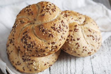 Köy ahşap masada keten tohumlu taze pişmiş ekmek ruloları.