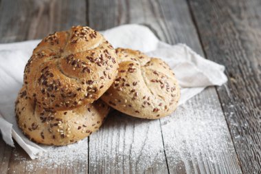 Köy ahşap masada keten tohumlu taze pişmiş ekmek ruloları.