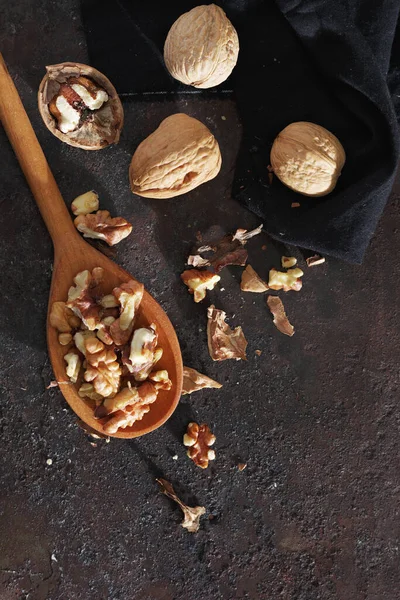 Ahşap kaşıkta cevizler ve grunge metal arka planda, üst manzara.