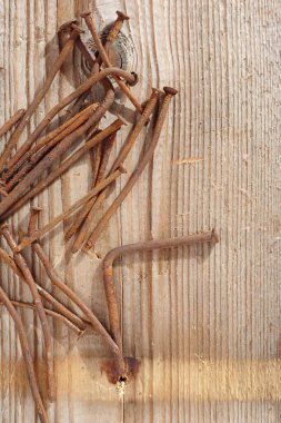 Old rusting nails on a wooden board background, top view