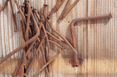 Old rusting nails on a wooden board background, top view