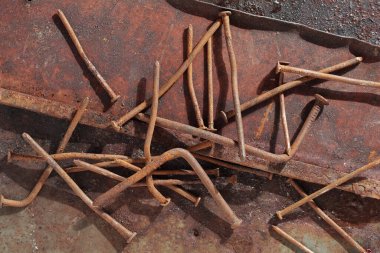 Old rusting nails on a grunge metal background, top view