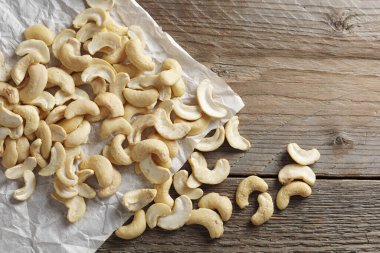 Cashew or Indian nuts on crumpled paper on wooden background, top view 